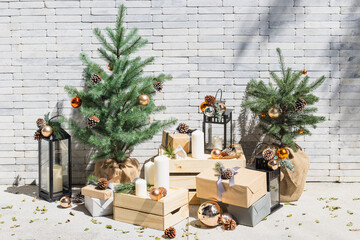 Christmas and New Year decoration with gift boxes, candles and fir branches on white brick wall background
