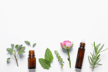 Bottles of essential oils, different herbs and rose flower on white background, flat lay. Space for text