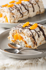 Swedish dessert Budapest roll filled with whipped cream and mandarins close-up in a plate on the table. Vertical