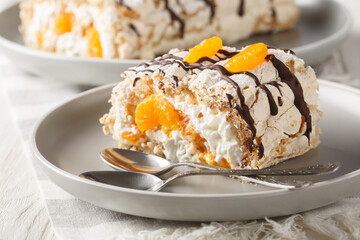 Gluten-free traditional Swedish dessert Budapest roll filled with whipped cream and tangerines close-up in a plate on the table. Horizontal