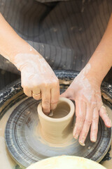 Hands of potter stained with pottery clay. Person is making pottery or ceramic on potter's wheel