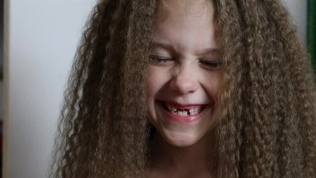 Cute little girl smiles and shows her fallen front milk teeth. Teeth growth. Close-up. Portrait of a 6-year-old rebec