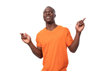 young happy american man dressed in basic orange t-shirt experiencing joy on white background with...