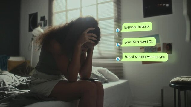 Stressed black schoolgirl receiving bullying messages on mobile phone from online haters and having mental breakdown at home, CG animated text appearing in copy space