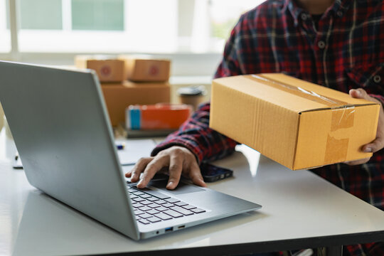 Small business startup SME business owners use smartphones or tablets to receive and monitor online orders to prepare product boxes for delivery. Close-up pictures