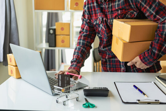 Small business startup SME business owners use smartphones or tablets to receive and monitor online orders to prepare product boxes for delivery. Close-up pictures