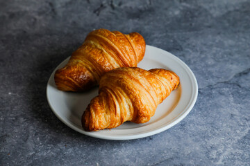 Plain Croissant served in plate isolated on grey background side view of french breakfast baked food item