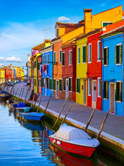 Burano island in Venice, Veneto region, Italy picturesque over canal with boats among old colourful houses stone streets