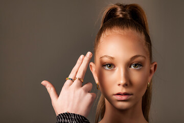 Portrait of teenage chic lady model with gesture fingers gun at head, looking at camera. Perfect teen cover girl 13 year old posture, studio shot. Fashion image style concept. Copy ad text space - obrazy, fototapety, plakaty