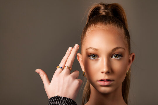 Portrait Of Teenage Chic Lady Model With Gesture Fingers Gun At Head, Looking At Camera. Perfect Teen Cover Girl 13 Year Old Posture, Studio Shot. Fashion Image Style Concept. Copy Ad Text Space