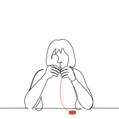 woman sitting at the table threads the eye of a needle - one line art vector. concept of sewing by hand or embroidering