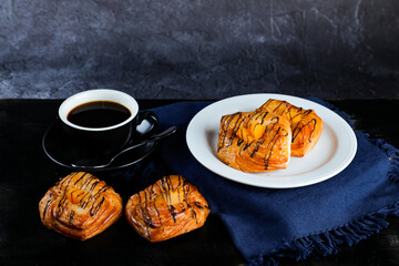 Peach Danish pastry puff served in plate with cup of black coffee isolated on napkin side view of...