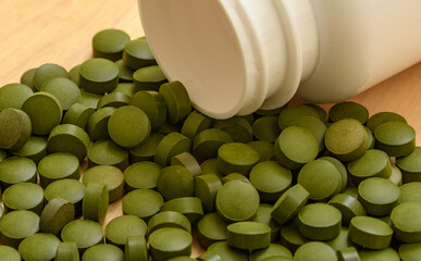 Zielone tabletki wysypane z pojemnika, spirulina z bliska © Paweł Kacperek