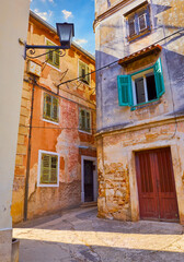Fototapeta na wymiar Lovran, Istria, Croatia. Vintage medieval buildings and houses at narrow lanes of old town. Stone wallswooden doors windows. Sunny evening time