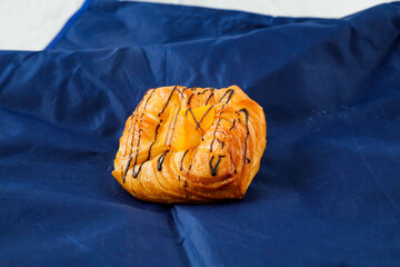 Peach Danish pastry puff isolated on blue napkin side view of french breakfast baked food item