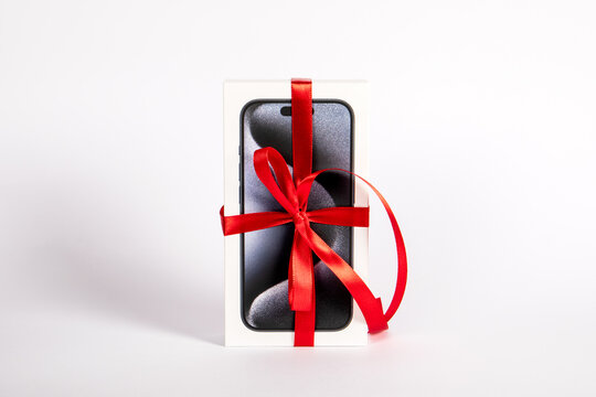 Box of the Iphone 15 Pro on on a white background. Gift with a red ribbon
