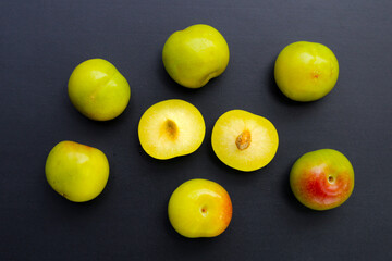 Fresh green plum fruit on dark background.