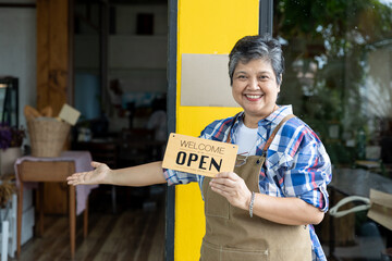 Senior woman business owner Holding an open sign at the door looking outside waiting for customers after lockdown small business owner Food and Drink Business open again