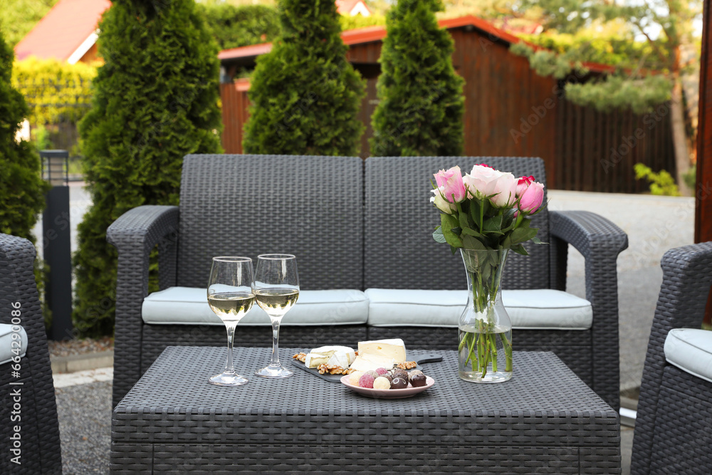 Canvas Prints Vase with roses, glasses of wine and food on rattan table on outdoor terrace