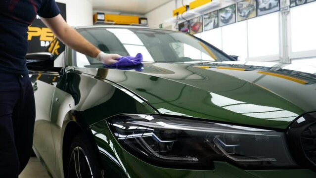 Staff wear Chemical protective clothing at work. Automobile industry. Car wash and coating business with ceramic coating.Spraying the varnish to the car. Concept of: Car protective, Service, Shine.	
