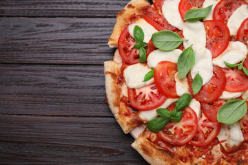Delicious Caprese pizza with tomatoes, mozzarella and basil on dark wooden table, top view. Space for text
