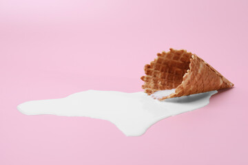 Melted ice cream and wafer cone on pink background