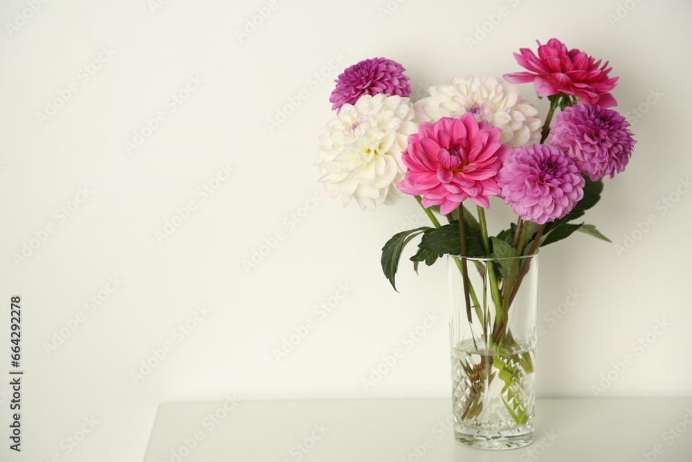 Sticker Bouquet of beautiful Dahlia flowers in vase on table near white wall, space for text