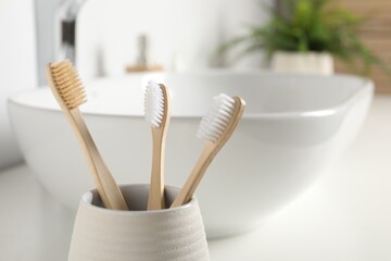 Bamboo toothbrushes in bathroom, closeup. Space for text
