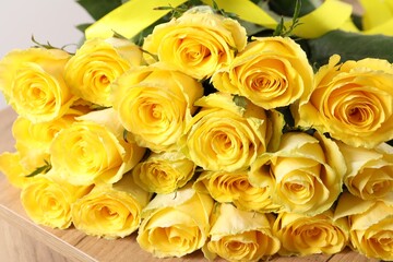 Beautiful bouquet of yellow roses on wooden table, closeup