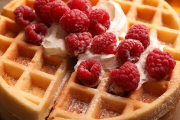 Tasty Belgian waffle with fresh raspberries and whipped cream, closeup