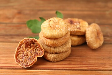 Tasty dried figs and green leaf on wooden table, closeup