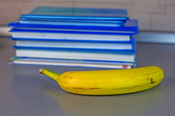 banana lies next to a stack of textbooks. back to school