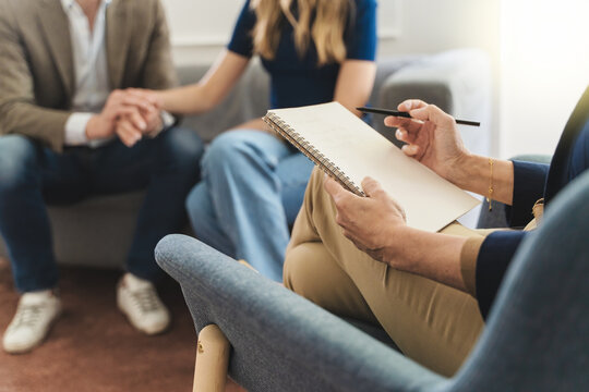 Couple Therapy Insight: Focus on Therapist's Notebook with Young Married Couple in Background