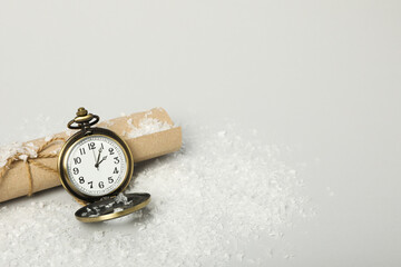Pocket watch with snow on a light background.