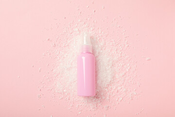 Cosmetic bottle and snow on pink background, top view