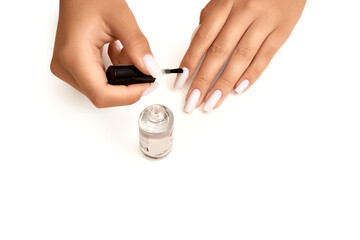 Woman with beautiful hands painting her long nails with transparent enamel