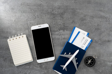 Passport with boarding pass and smartphone on stone texture background. Tourism and travel concept. Top view. Flat lay.