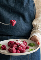Italian gnocchi beetroot . Traditional Italian food in a bowl is held by a woman in an apron....