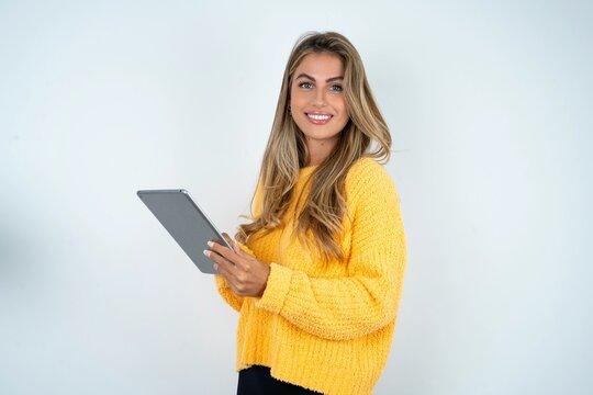 Photo of happy cheerful smart Beautiful caucasian woman wearing yellow jumper hold tablet browsing internet