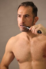 Przystojny, dojrzały mężczyzna myje zęby.
A man brushes his teeth with an electric toothbrush.