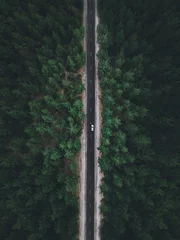 Gartenposter Straße im Wald Aerial view taken by drone of a car driving on a forest road in autumn