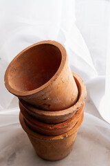 Untreated clay pots. Orange color. Autumn mood. Against the background of a delicate white curtain. Daylight. Natural color.