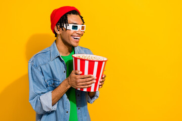 Photo of positive good mood man wear jeans outfit earrings looking empty space fascinating film isolated on vivid yellow color background
