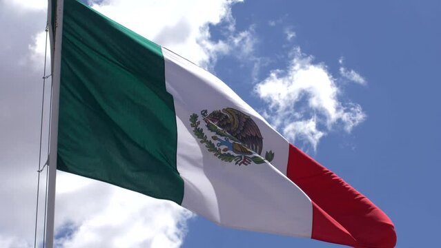 Slow-motion Mexican flag moving with the wind on a blue sky day