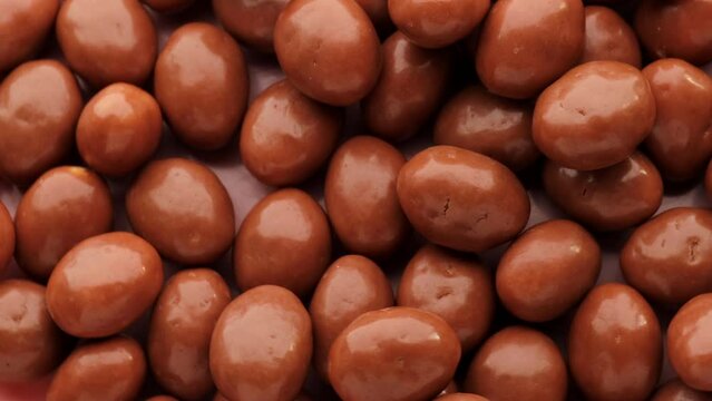 Pistachios covered in chocolate, rotation in circle. Nuts in chocolate, Turning. chocolate background. Chocolate coated nut