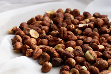 Fresh, young, unroasted hazelnuts or hazelnut kernels. Against the background of a delicate white curtain. Daylight. Natural color.