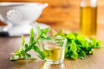 Sweet mint syrup and mint leaves on wooden table.