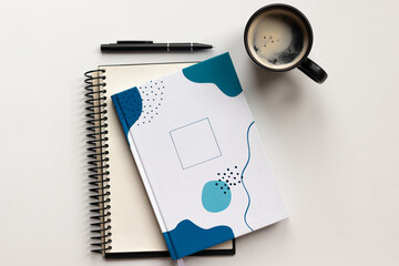 Top view of modern office desk with creative notebooks, pencil and coffee cup on white backdrop....