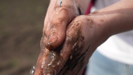 Clean fresh water pouring into dirty hands of person. Farmer washes his dirty hands. Man washes his hands after working with earth. Clean water splashes on hands of village gardener. Ecology concept