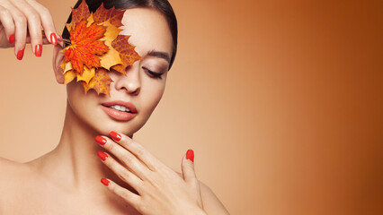 Portrait of beautiful young woman with autumn leafs. Healthy clean fresh skin natural make up beauty eyes and red nails